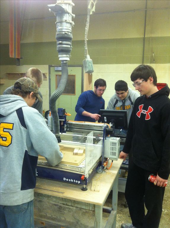 Alcona woodworking students using their CNC machine to make a custom sign.
